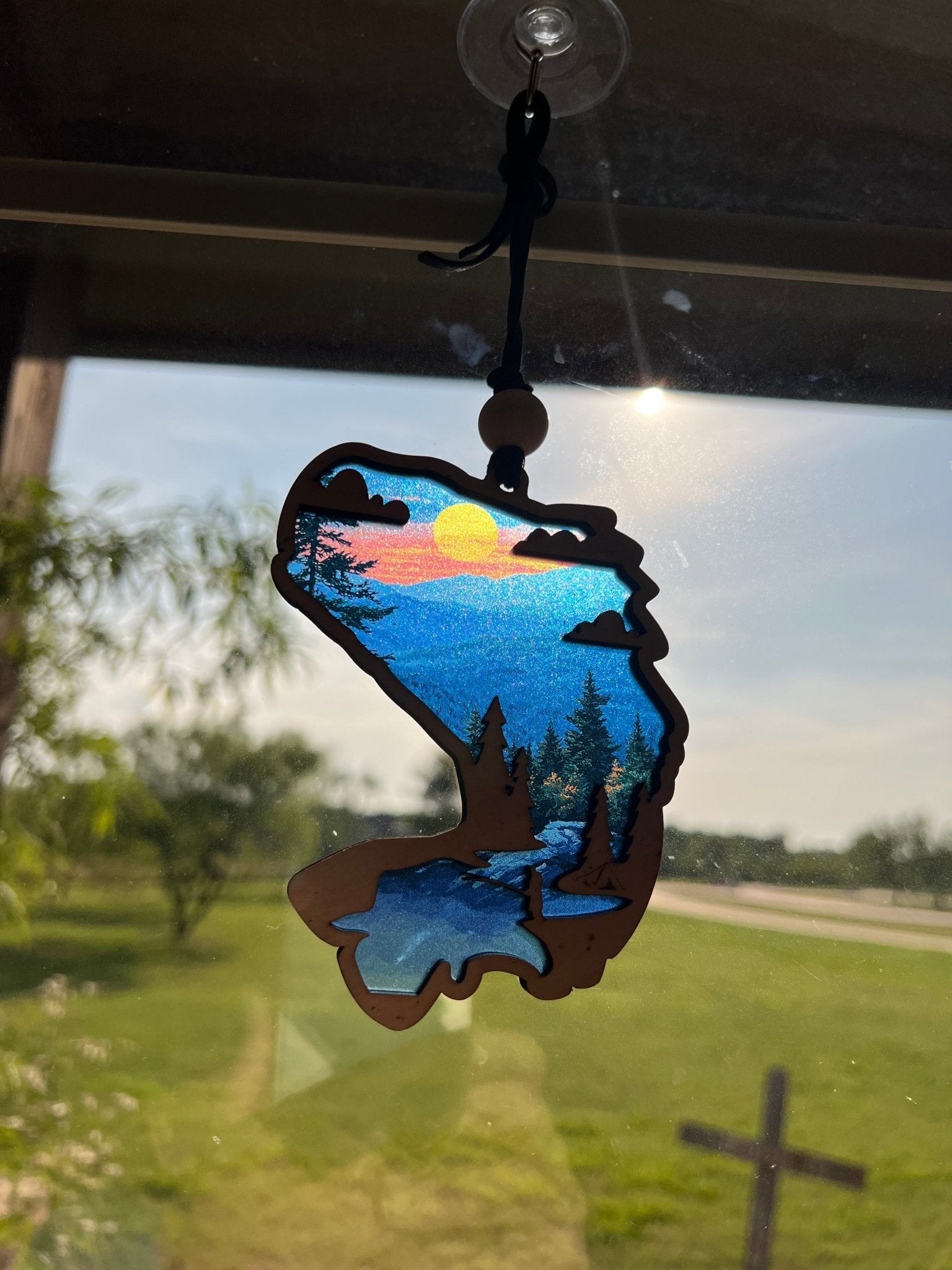 Bass Fish Suncatcher made of wood and acrylic with a stained glass effect and multicolor elements in sunlight.