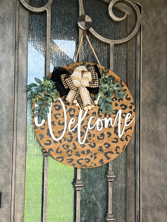 A rustic wooden door hanger with leopard print design, perfect for chic decor hanging on a metal door.