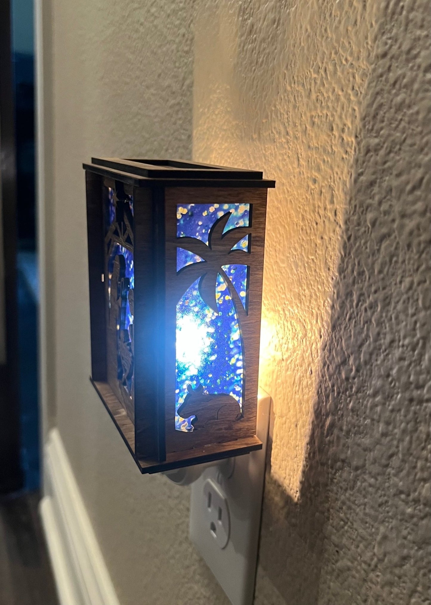 A Christmas Nativity Lantern Nightlight in golden oak with wood and acrylic materials - lit right side with lights on.