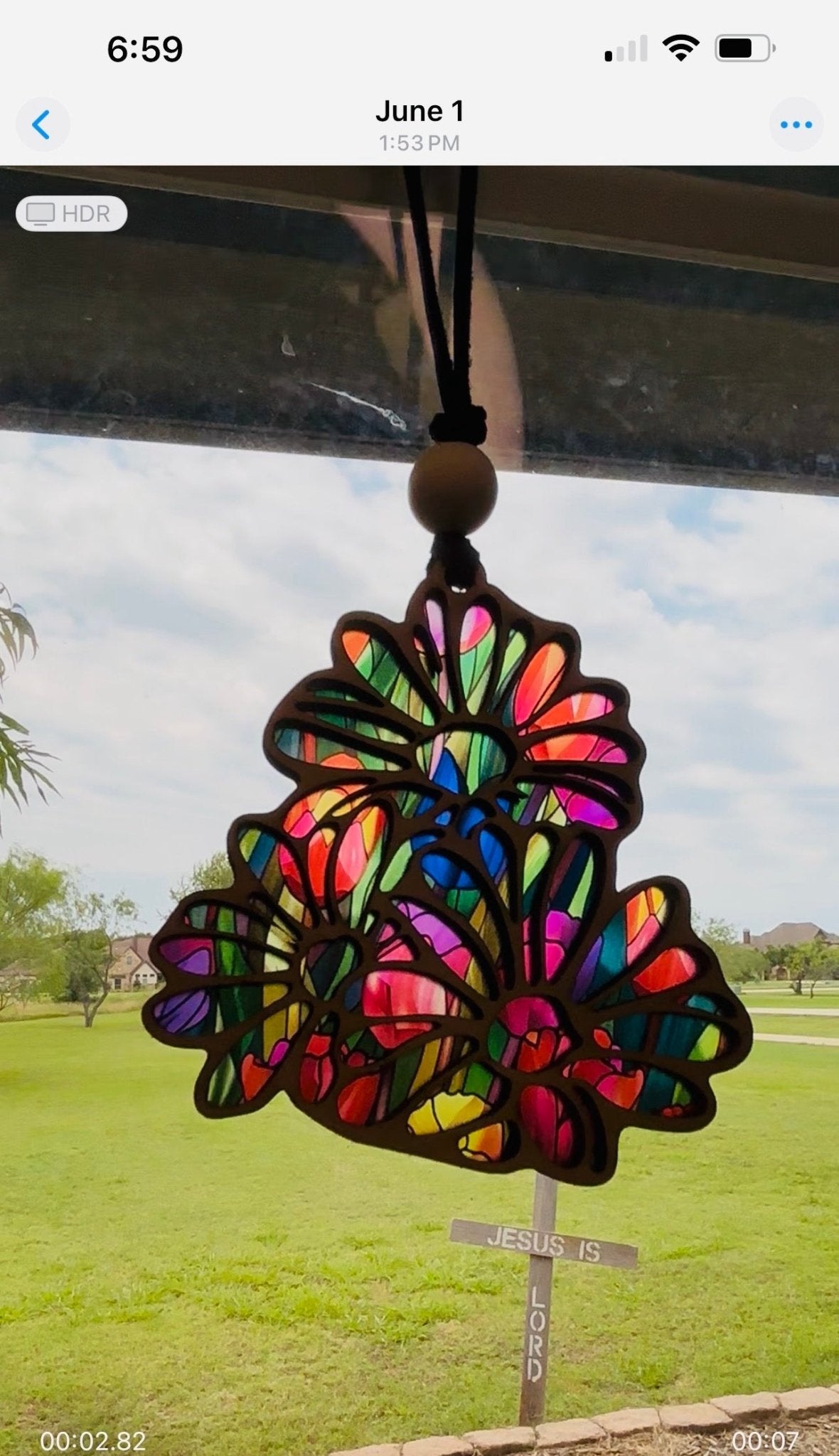 Daisy-shaped suncatcher with stained glass effect in wood and acrylic in sunlight.