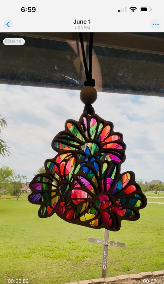 Daisy-shaped suncatcher with stained glass effect in wood and acrylic in sunlight.