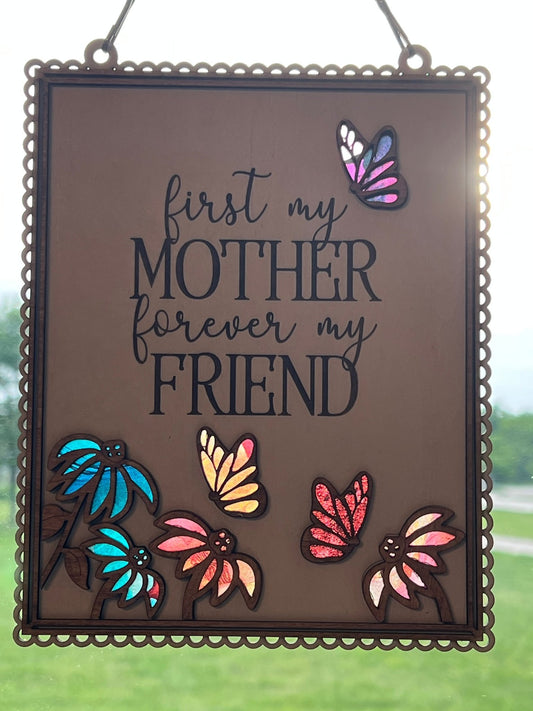 Colorful Mother Butterfly Suncatcher made of acrylic and wood, hanging in a window in sunshine.