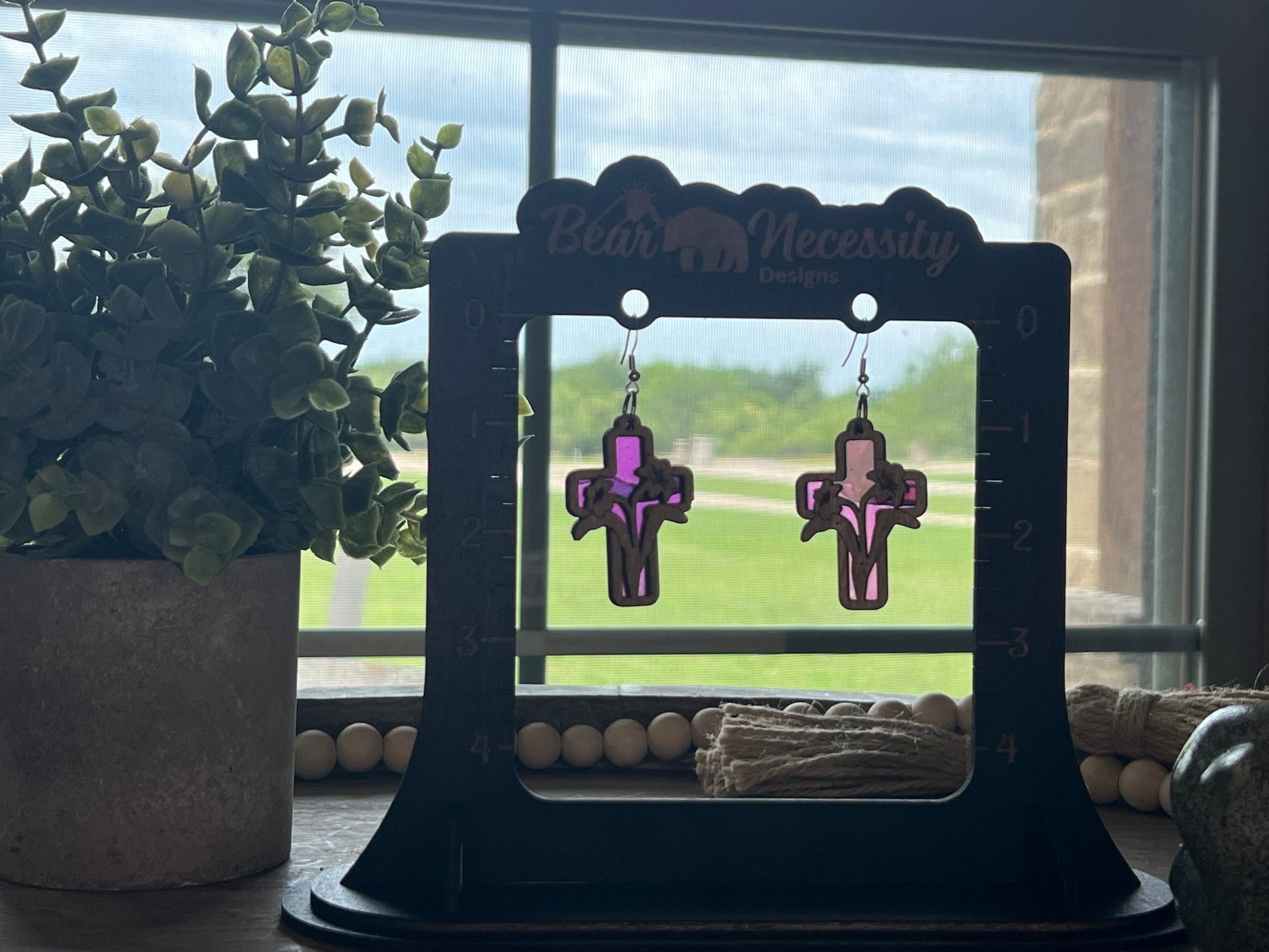 Lily Cross Suncatcher Earrings with stained glass effect in wood and acrylic in sunlight.