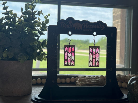 Pink butterfly earrings made from wood and acrylic with a stained glass effect in sunlight.